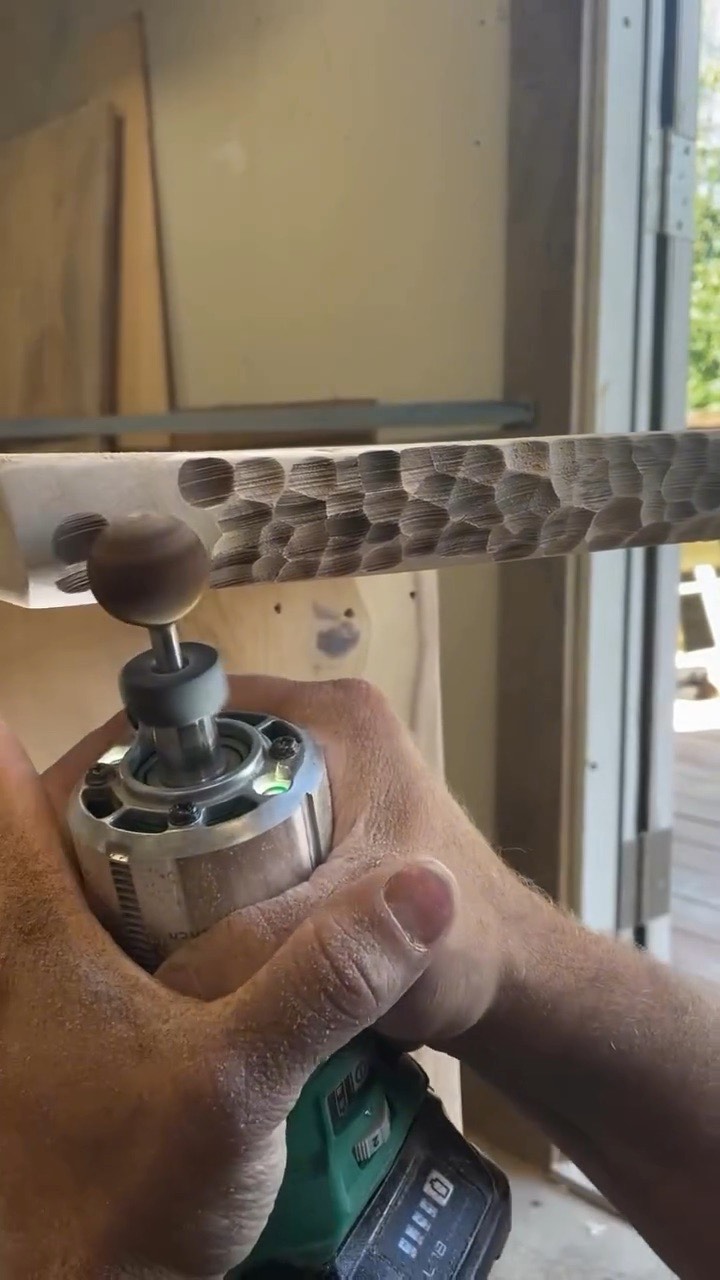 A Kutzall burr on a drill carving the edge of a wood board
