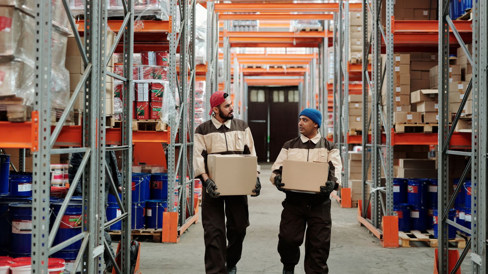Warehouse workers carrying boxes through a fulfillment aisle